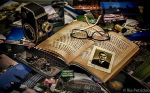 Oral History symbolisiert durch ein offenes Buch mit Foto dahinter andere Bilder und eine Kamera