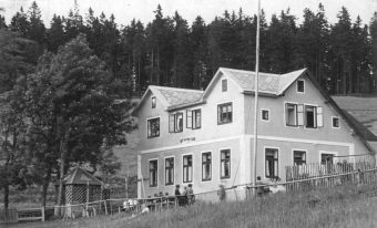 Foto des Naturfreundehaus Karlsbader Hütte in sanfter Hügellandschaft mit Wanderern im Freien